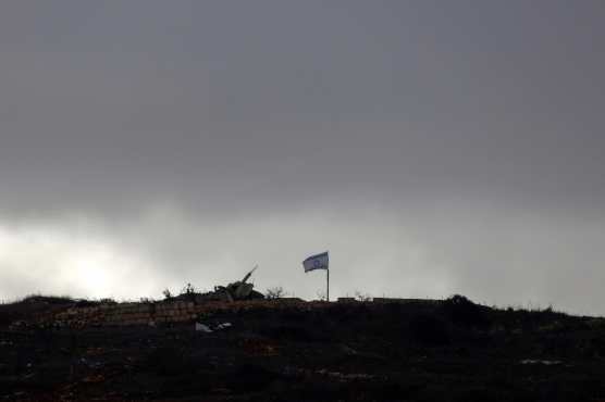 This picture taken from a position in northern Israel, near the border with Lebanon, shows an Israeli flag fluttering in the rubble of a destroyed building in the southern Lebanese village of Hula on November 25, 2024, amid the ongoing war between Israel and Hezbollah. Israeli ground forces have entered several villages and towns near Lebanon's southern border, including Khiam, where the Lebanese National News Agency (NNA) on November 25 reported clashes with Hezbollah fighters. (Photo by Jalaa MAREY / AFP)