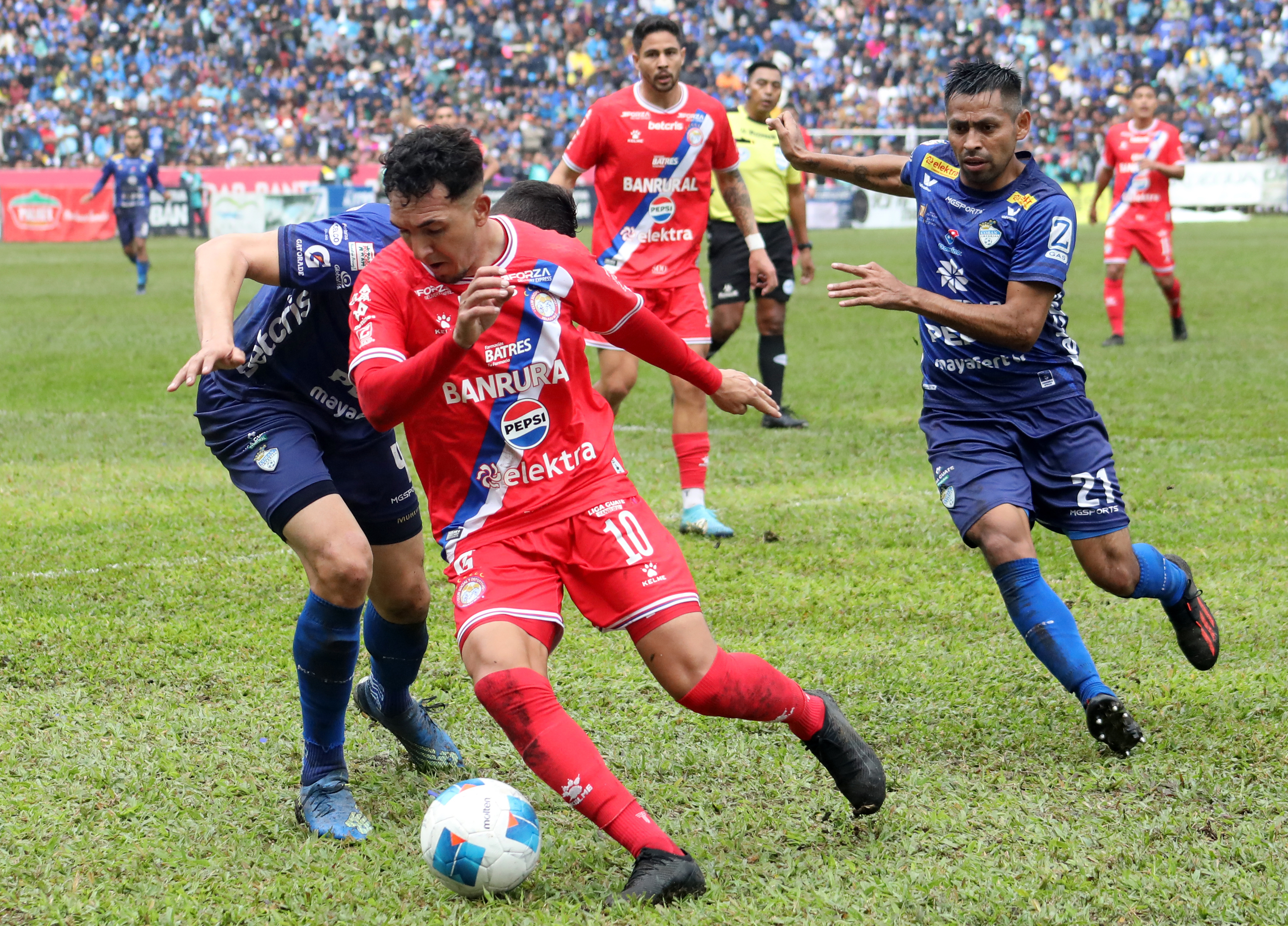 Thales Moreira y Byron Leal de Cobán Imperial disputan un balón con Oscar Raí Villa de Xelajú MC.