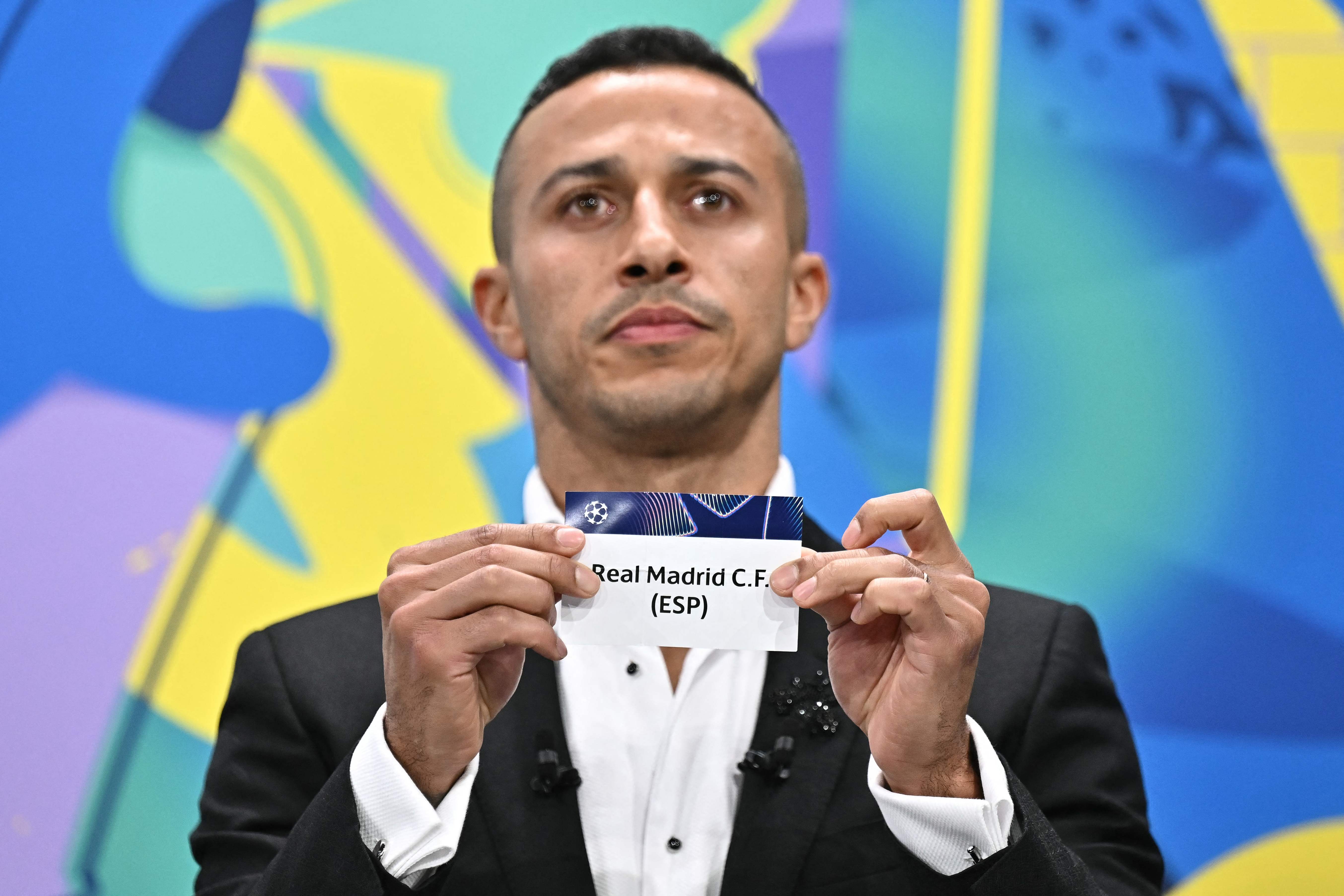 El exjugador español Thiago Alcántara sostiene el papel con el nombre del Real Madrid.