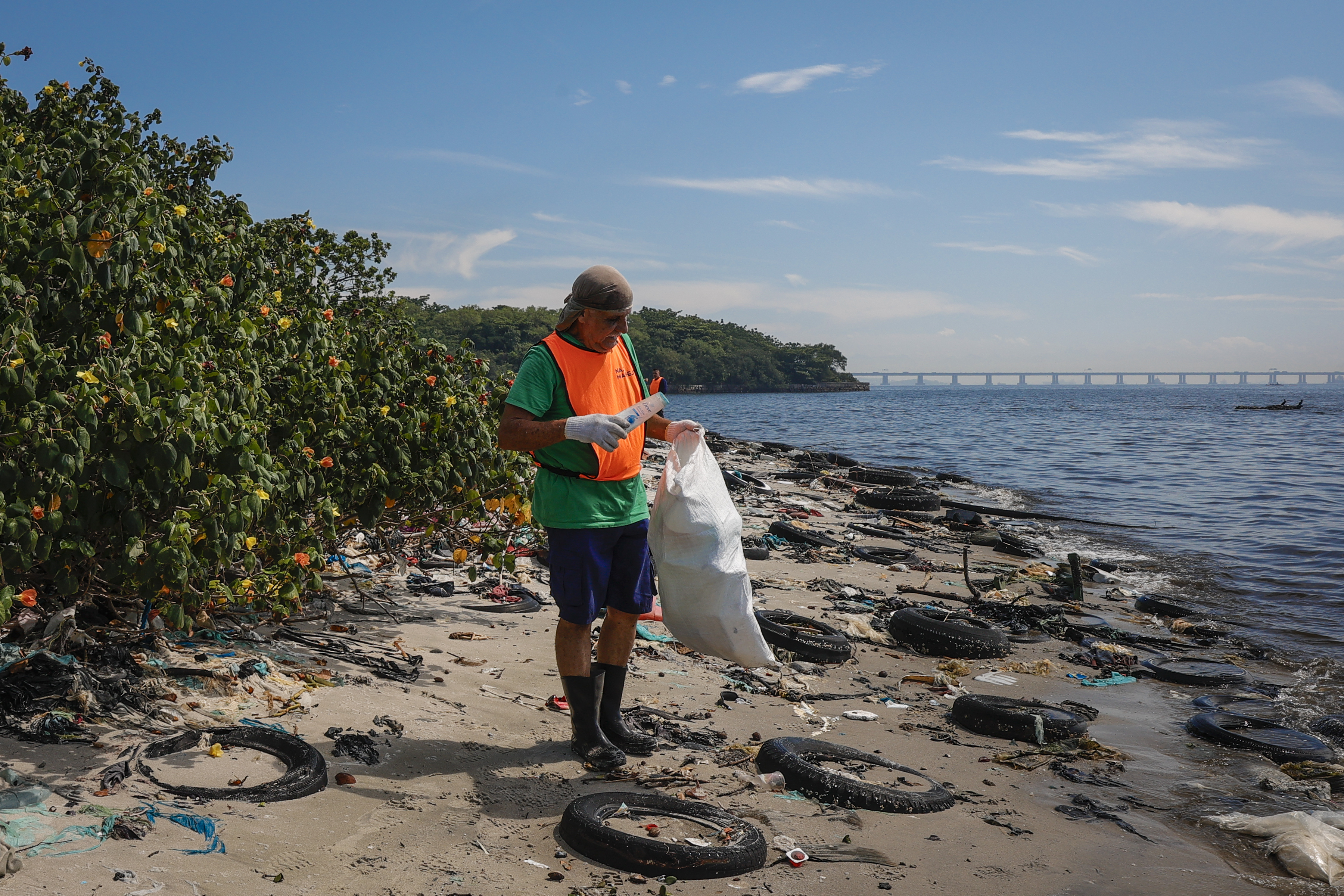 ACOMPAÑA CRÓNICA: BRASIL MEDIOAMBIENTE. AME8116. RÍO DE JANEIRO (BRASIL), 08/02/2025.- Un colaborador de la ONG Nas Marés recoge basura en la Isla de Pombeba este viernes, en la Bahía de Guanabara, en Río de Janeiro (Brasil). Un pequeño islote ubicado a pocos metros del puerto de Río de Janeiro y con sus playas tapizadas por unas 80 toneladas de basura es la muestra del fracaso de la renovada promesa de las autoridades de este estado brasileño de descontaminar la bahía de Guanabara. EFE/ André Coelho