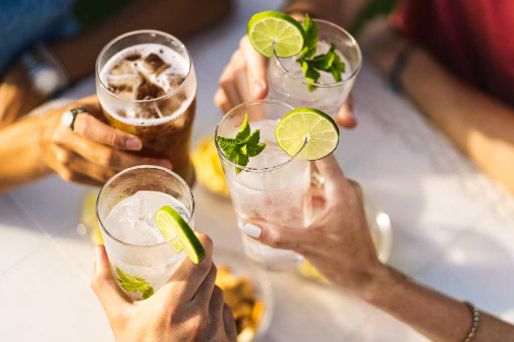 Grupo de personas celebrando el tostamiento con cócteles - detalles recortados con enfoque en las manos - concepto de estilo de vida de las personas, bebidas y alcohol - sin caras - personas irreconocibles