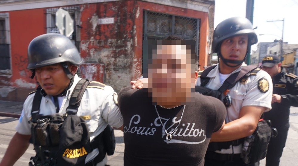 Uno de los detenidos durante los disturbios en la zona 1 de la capital es trasladado por agentes de la PNC. (Foto Prensa Libre: Daniel Samayoa)