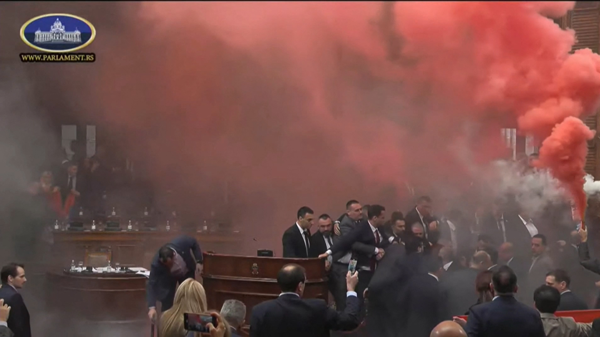 This frame grab from handout video footage taken and released by the National Assembly of the Republic of Serbia in Belgrade on March 4, 2025 shows Serbian opposition lawmakers lighting flares and discharging suspected tear gas during the opening day of the spring session of parliament in a sign of support for ongoing anti-corruption protests. The footage shared online showed opposition members holding colourful flares and throwing what appeared to be smoke cannisters during the legislative session. Serbia has been rocked for months by student-led anti-corruption protests following the fatal collapse of a train station roof last year that killed 15 people. (Photo by Handout / National Assembly of the Republic of Serbia / AFP) / RESTRICTED TO EDITORIAL USE - MANDATORY CREDIT "AFP PHOTO / National Assembly of the Republic of Serbia " - NO MARKETING NO ADVERTISING CAMPAIGNS - DISTRIBUTED AS A SERVICE TO CLIENTS