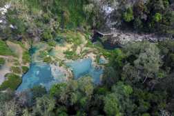 Aerial view of Semuc Champey National Park in Alta Verapaz, Guatemala, taken on March 13, 2025. The Natural monument of Semuc Champey, which in the local Qeqchi Maya dialect means where the river disappears into the earth, consists of a natural 300 meters long limestone bridge, under which the Cahabon River passes. Atop the bridge there are a series of stepped pools, ranging from turquoise to emerald-green, good for swimming. (Photo by JOHAN ORDONEZ / AFP)