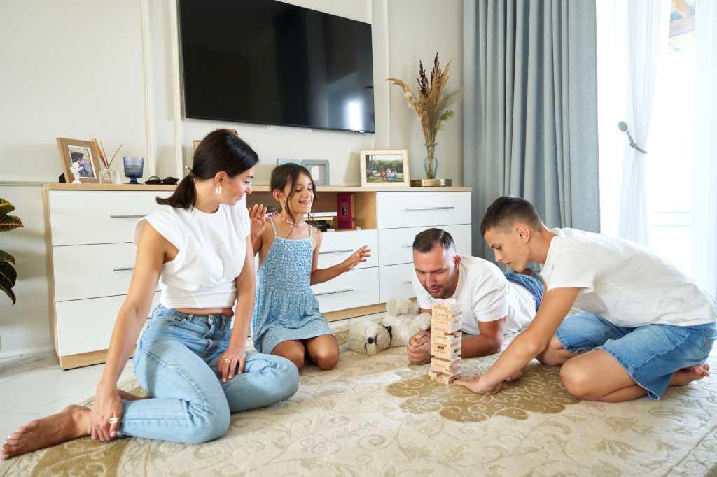 Familia jugando un juego de jenga en el suelo en una sala de estar brillante durante la tarde