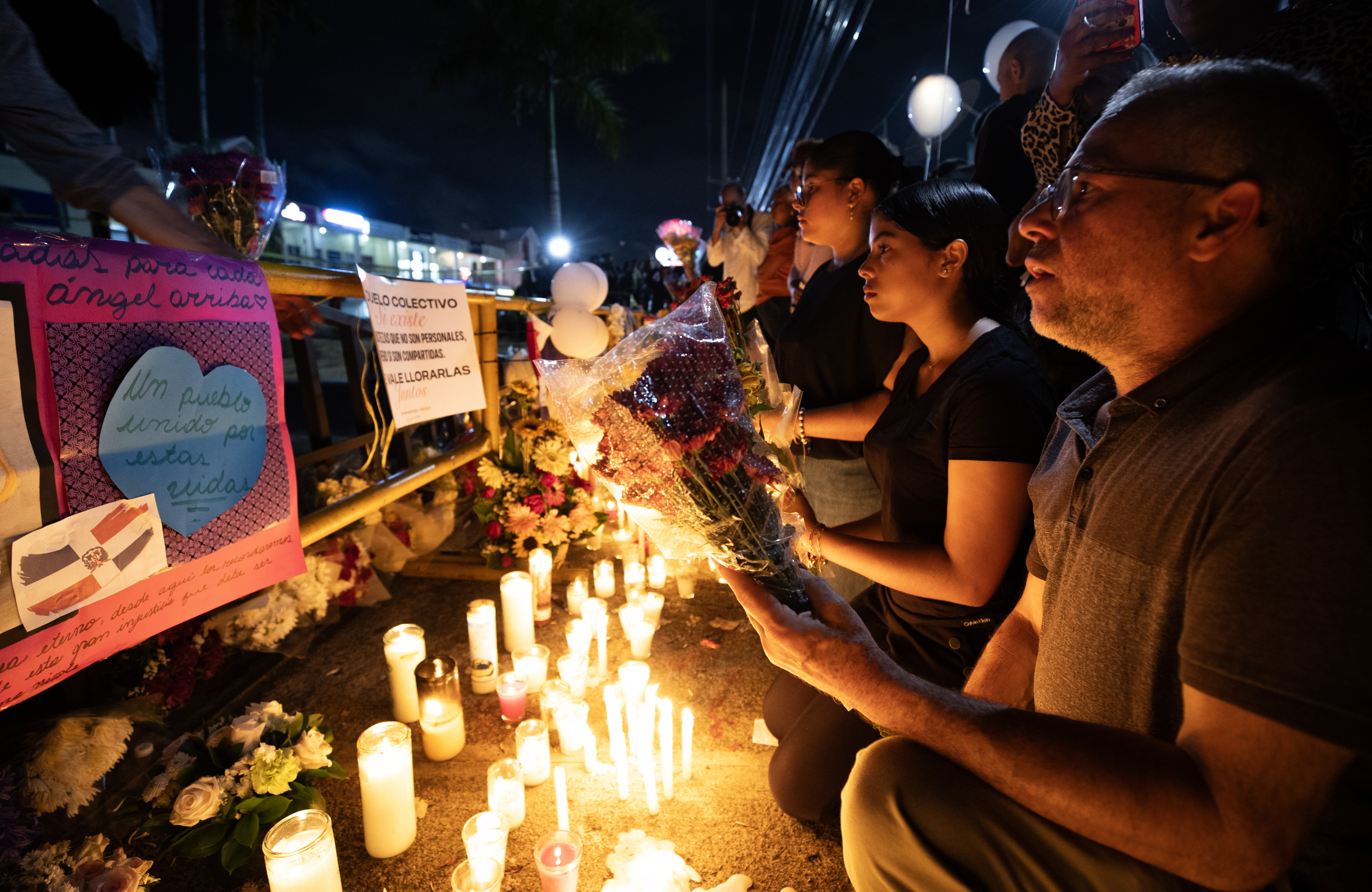 AME8518. SANTO DOMINGO (REPÚBLICA DOMINICANA), 11/04/2025.- Personas participan en una velatón este viernes en Santo Domingo (República Dominicana). Decenas de personas encendieron velones, portaron globos y depositaron flores en la parte frontal de la discoteca Jet Set, en Santo Domingo, donde la madrugada del martes pasado el derrumbe del techo causó la muerte de 221 personas y heridas a otras 189. EFE/Orlando Barría