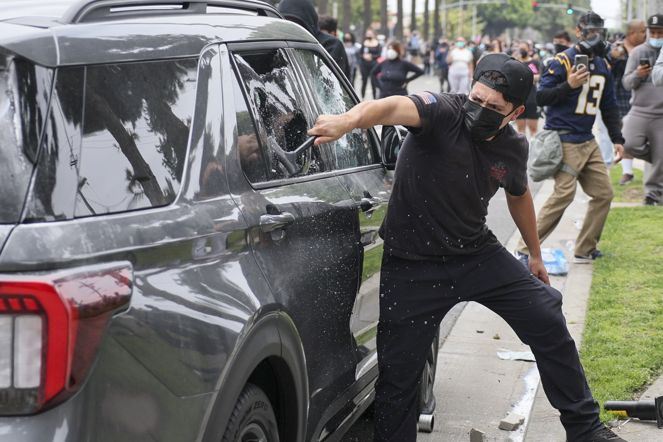Un manifestante rompe el vidrio de un vehículo de agentes federales, que participaron en el operativo antimigrante en Paramount, California, EE.UU. (Foto Prensa Libre: EFE)