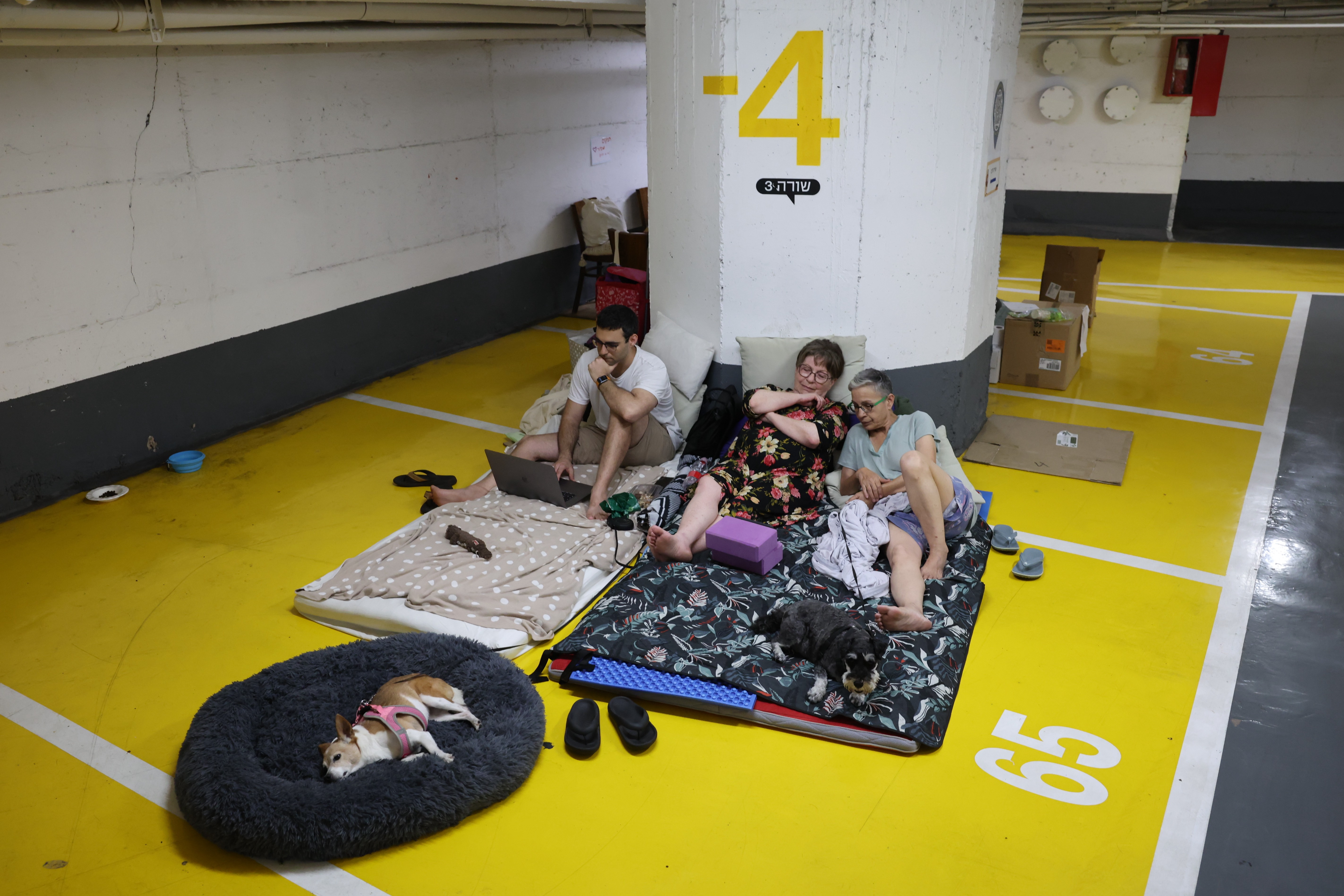 Personas y sus mascotas descansan en un bunker de Tel Aviv por los ataques con misiles de Irán sobre Israel. (Foto Prensa Libre: EFE) 