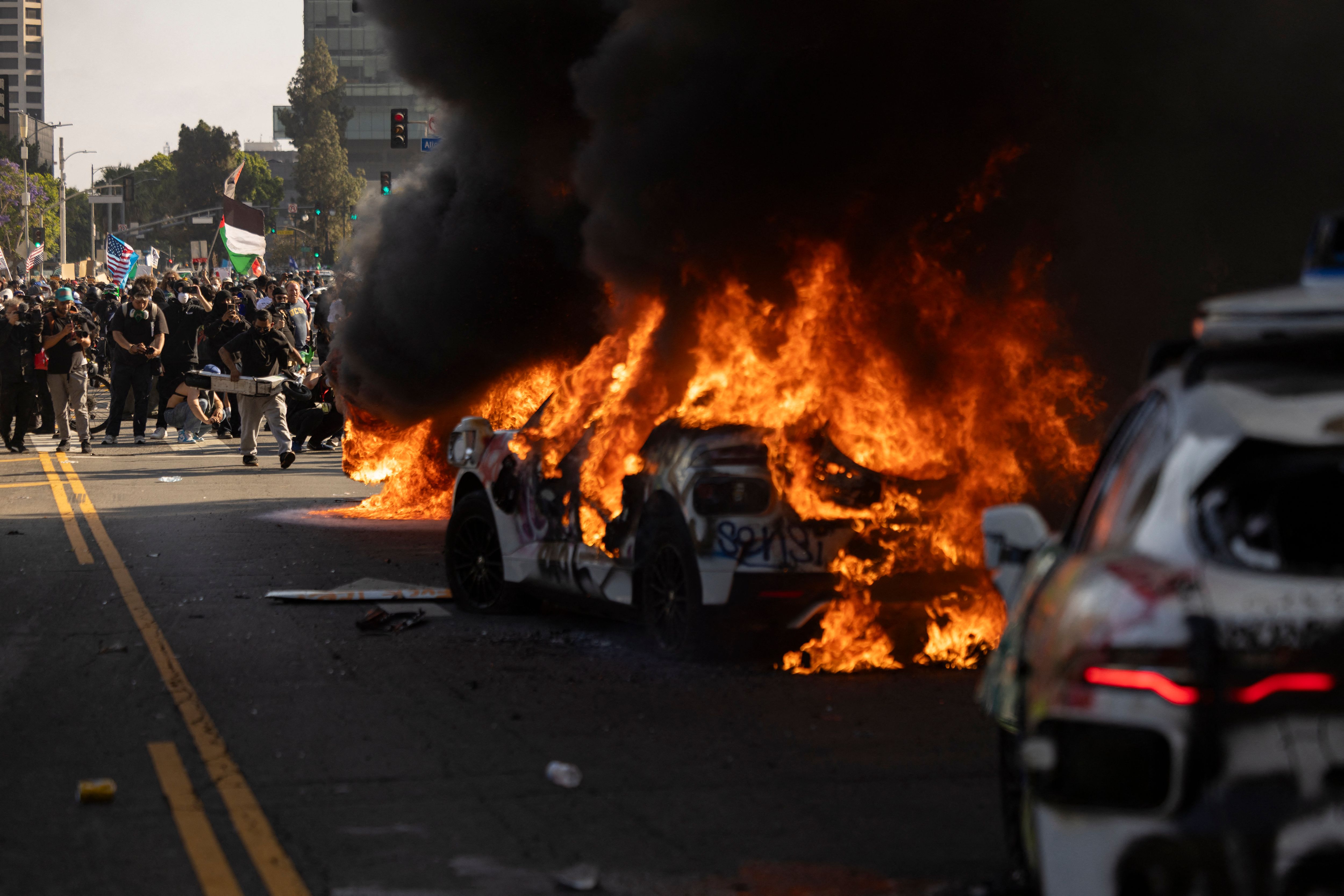 Vehículos son incendiados , mientras manifestantes se enfrentan con las fuerzas del orden cerca del edificio federal , durante una protesta en respuesta a las operaciones federales de inmigración en Los Ángeles, California, (Foto Prensa Libre: AFP)