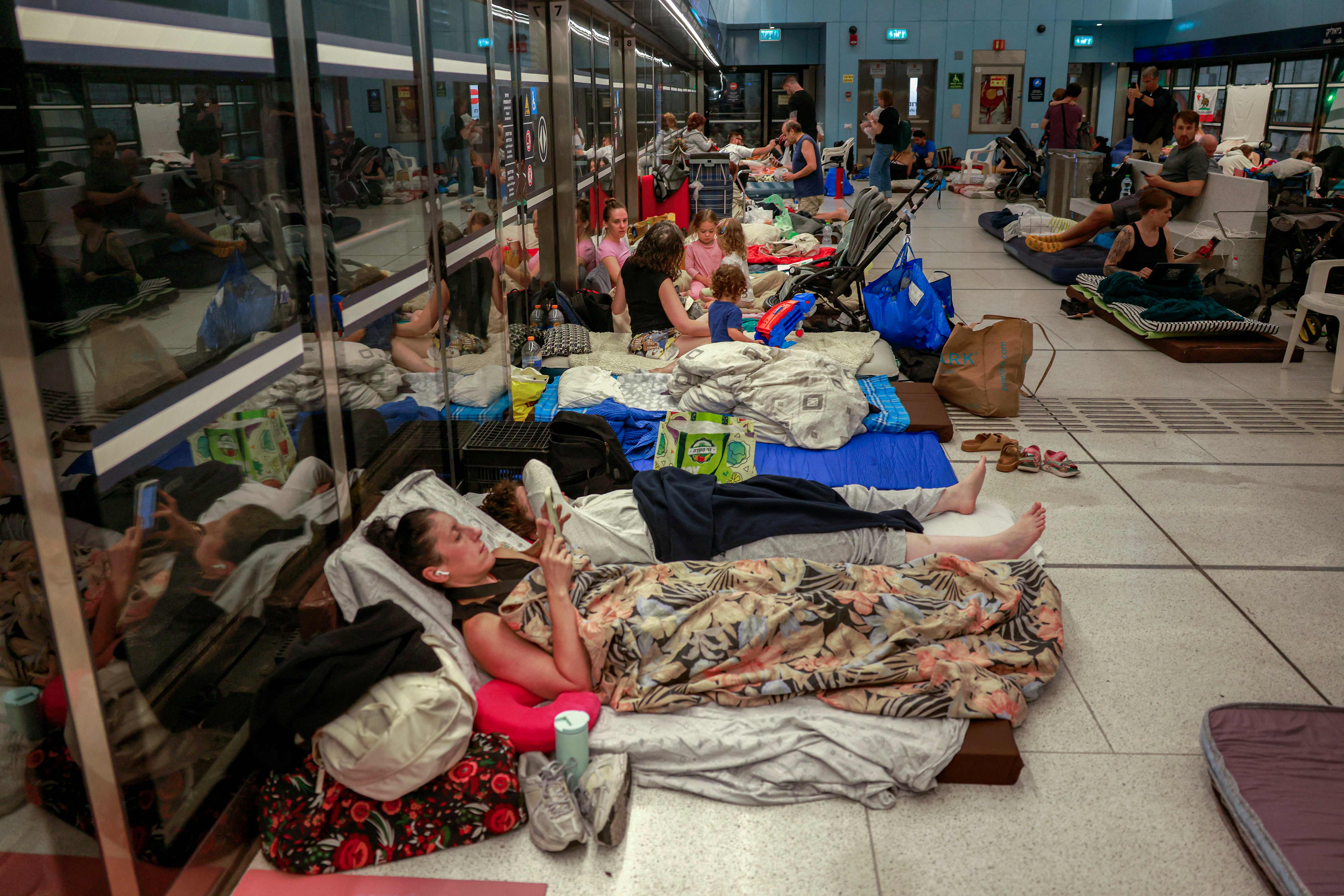 Con bolsas para dormir, personas pasan la noche en lugares inesperados, por seguridad ante los ataques entre Irán e Israel. (Foto Prensa Libre: AFP)