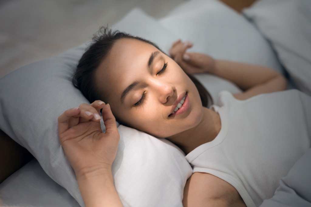 Mujer Joven Durmiendo En La Cama Cómoda Y Alegremente Con Rayo De Sol Amanecer En Su Cara