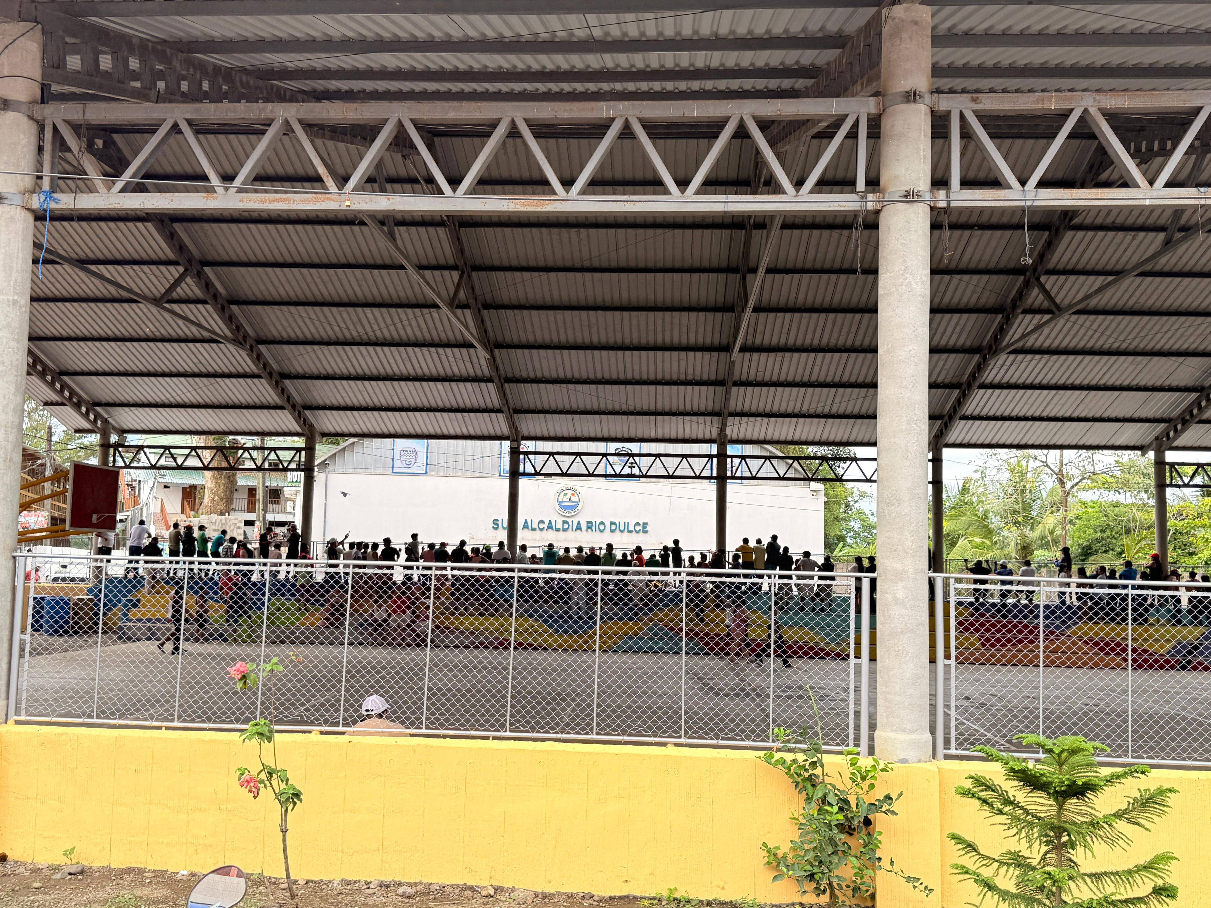 Pobladores se encuentran en las canchas deportivas bajo el puente de río dulce, a la espera de una respuesta sobre la reunión que se lleva dentro de la sub alcaldía. (Foto Prensa Libre: Joseph Domínguez)