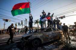 Demonstrators stand on top of a charred vechicle during a protest following federal immigration operations, in the Compton neighborhood of Los Angeles, California on June 7, 2025. US President Donald Trump deployed 2,000 troops on June 7, 2025 to handle escalating protests against immigration enforcement raids in the Los Angeles area, a move the state's governor termed "purposefully inflammatory." Federal agents clashed with angry crowds in a Los Angeles suburb as protests stretched into a second night Saturday, shooting flash-bang grenades and shutting part of a freeway amid raids on undocumented migrants, reports said. (Photo by RINGO CHIU / AFP)