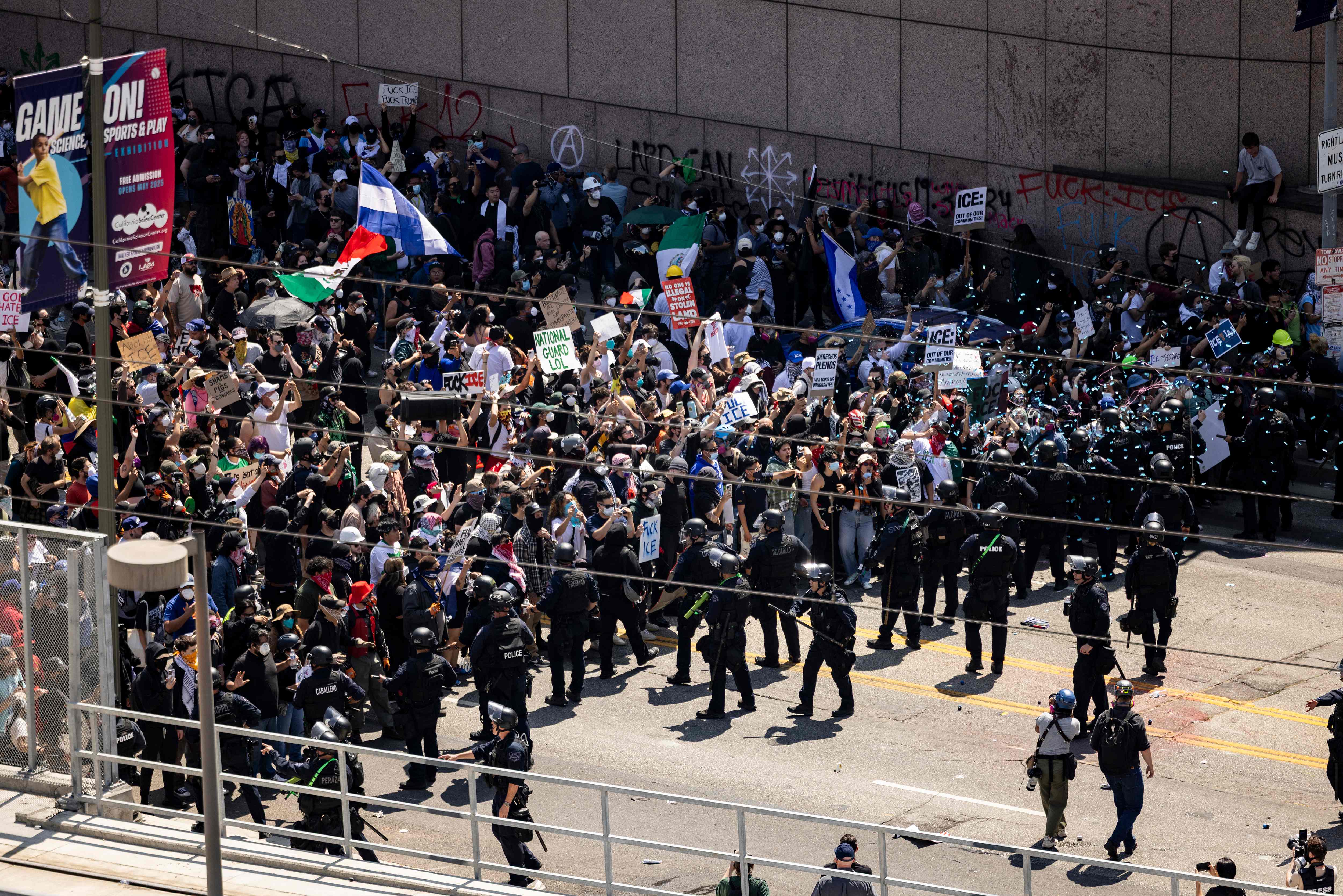 Law enforcement clash with demonstrators in front of the federal building during a protest following federal immigration operations, in Los Angeles, California on June 8, 2025. US President Donald Trump deployed 2,000 troops on June 7 to handle escalating protests against immigration enforcement raids in the Los Angeles area, a move the state's governor termed "purposefully inflammatory." Federal agents clashed with angry crowds in a Los Angeles suburb as protests stretched into a second night Saturday, shooting flash-bang grenades and shutting part of a freeway amid raids on undocumented migrants, reports said. (Photo by ETIENNE LAURENT / AFP)