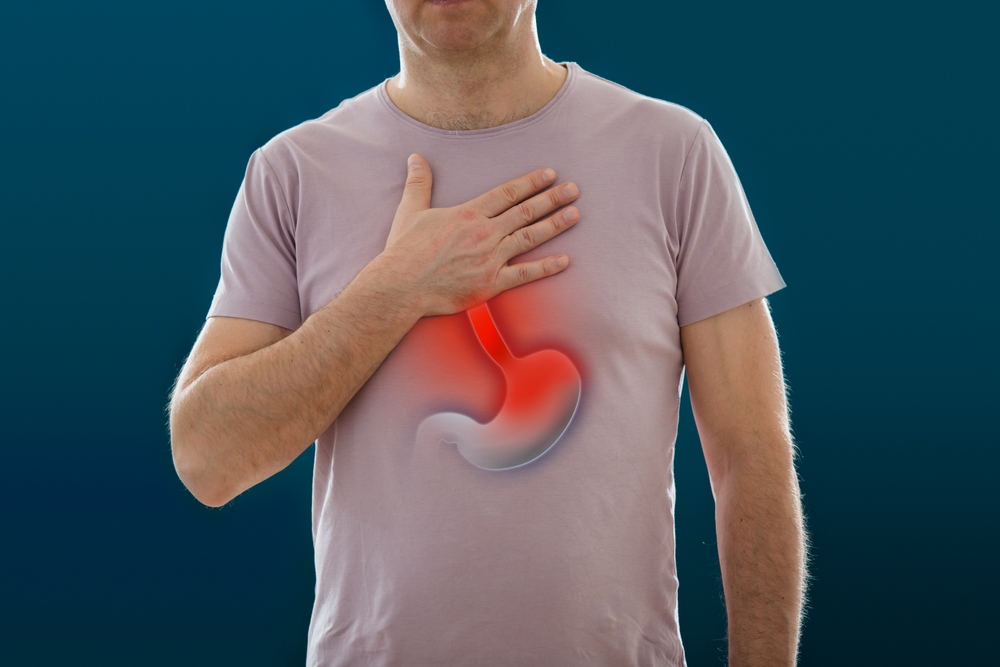 El hombre de pie sobre un fondo oscuro. Imagen de un sistema digestivo humano y del estómago con inflamación. Anatomía de un humano con ardor de estómago. Concepto médico, enfermedades intestinales