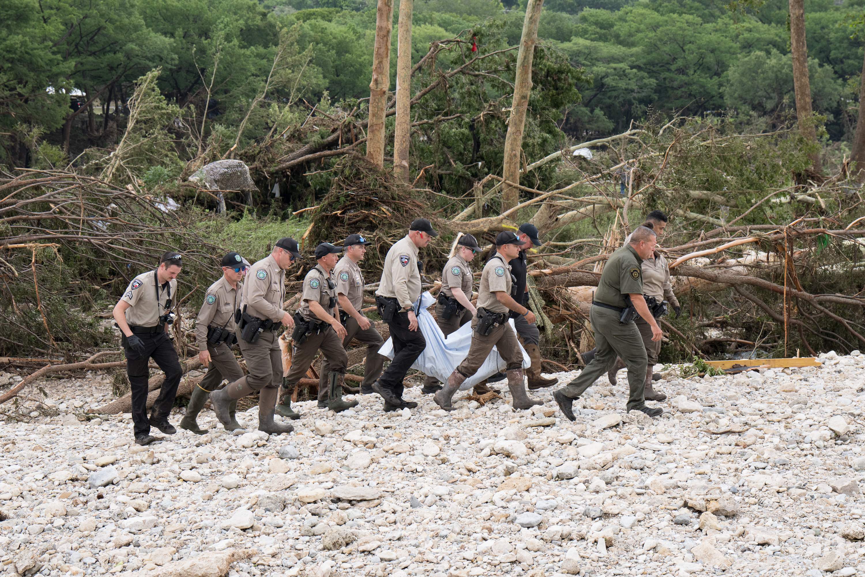 HUNT, TEXAS - JULY 05: Texas Game Wardens and local law enforcement carry the body of a flood victim from the banks of the Guadalupe River during recovery operations on July 5, 2025 near Hunt, Texas. Heavy rainfall caused flooding along the Guadalupe River in central Texas with at least 43 fatalities reported.   Eric Vryn/Getty Images/AFP (Photo by Eric Vryn / GETTY IMAGES NORTH AMERICA / Getty Images via AFP)