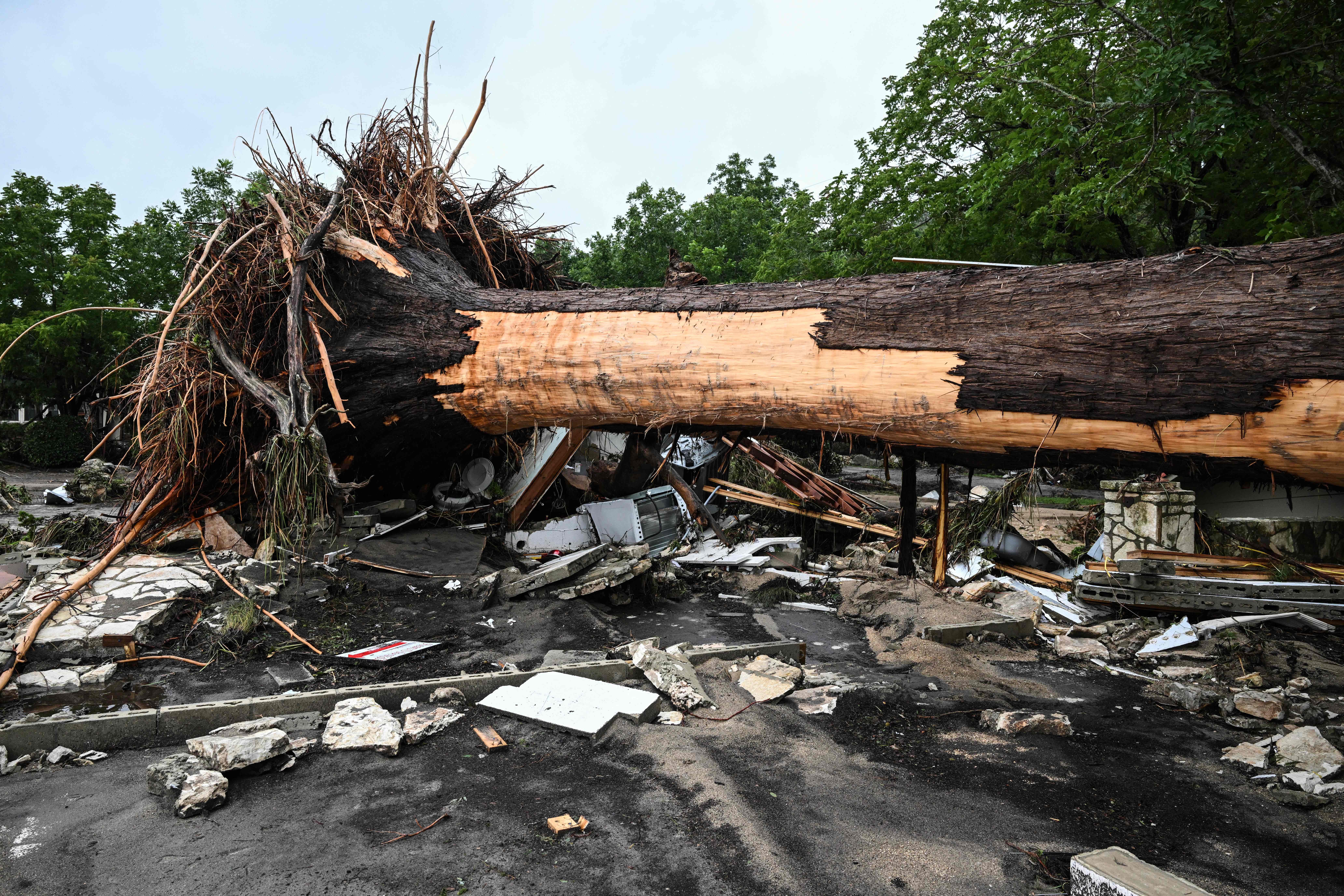 A large tree is uprooted outside of a home near Camp Mystic, the site of where at least 20 girls went missing after flash flooding in Hunt, Texas, on July 5, 2025. Rescuers were on Saturday searching for more than 20 girls missing from a riverside summer camp in the US state of Texas, after torrential rains caused devastating flooding that killed at least 27 people -- with more rain on the way. "So far, we've evacuated over 850 uninjured people, eight injured people and have recovered 27 deceased fatalities at this time. Of these 27, 18 are adults, nine are children," said Kerr Country Sheriff Larry Leitha on July 5. (Photo by RONALDO SCHEMIDT / AFP)
