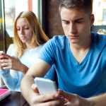 Portrait of group of friends using mobile phone in cafe.