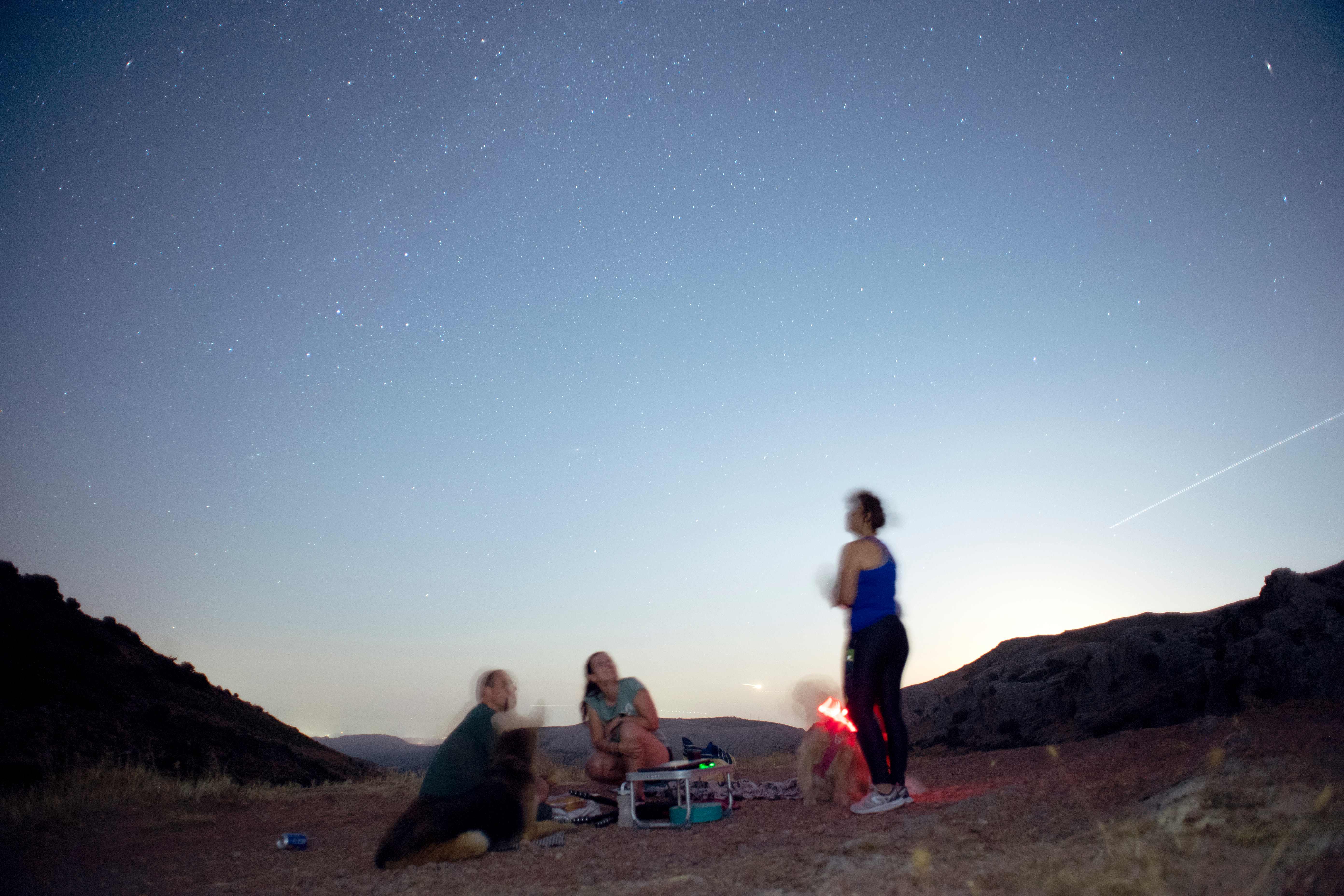 People look at meteor streaks across the sky against a field of stars during a meteor shower in Ronda, Andalusia, Spain on August 12, 2025. (Photo by JORGE GUERRERO / AFP)