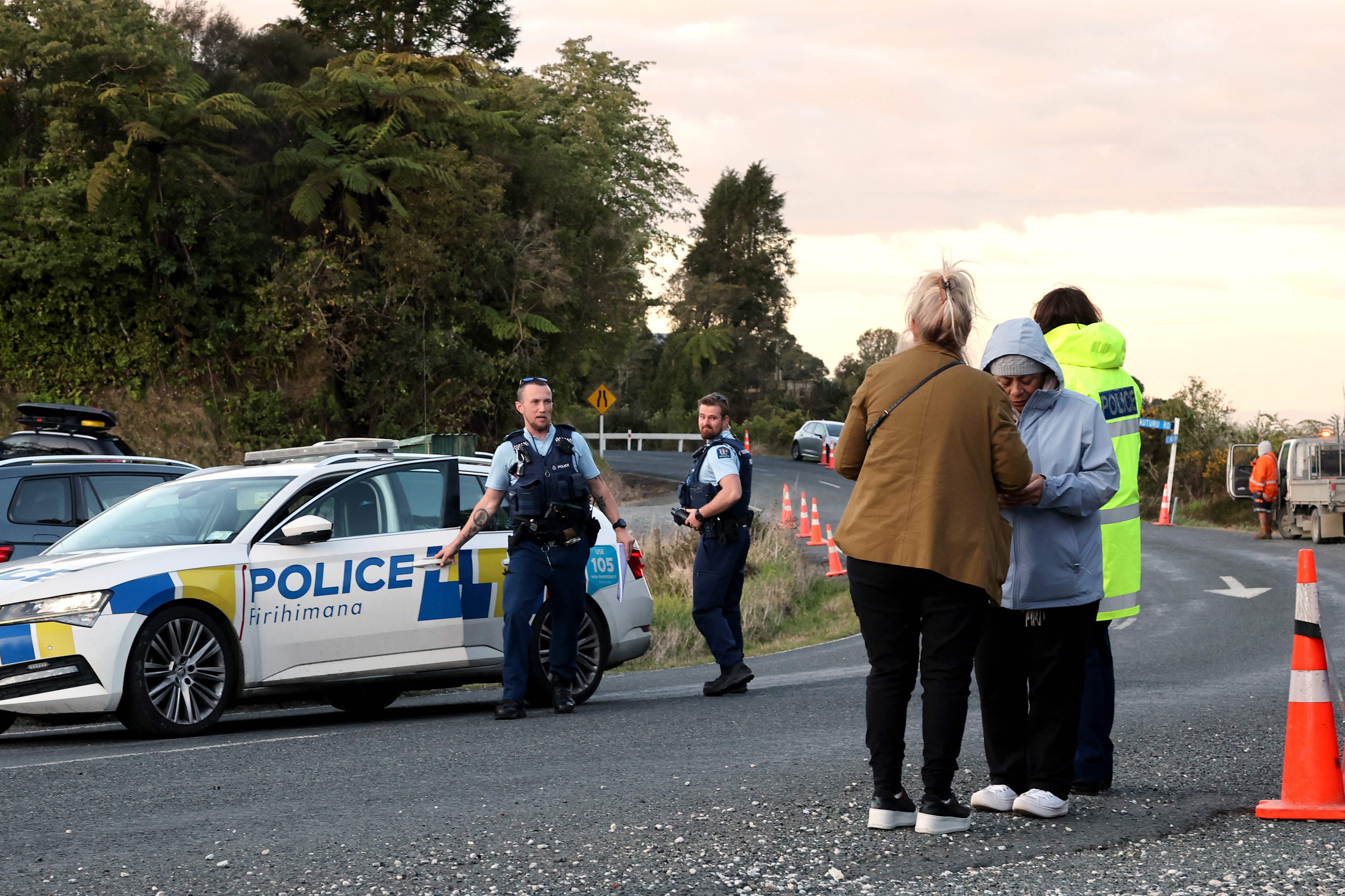 Police officers and locals stand near a roadblock where a police shootout occurred near the town of Piopio, located in New Zealands Waikato region on September 8, 2025. A New Zealand father who spent nearly four years on the run with his children was killed in a police shootout on September 8, authorities said. Tom Phillips, who absconded with his three children in December 2021 after a row with his former partner, died in the rolling hill country of the North Island's Waikato region. (Photo by DJ MILLS / AFP)