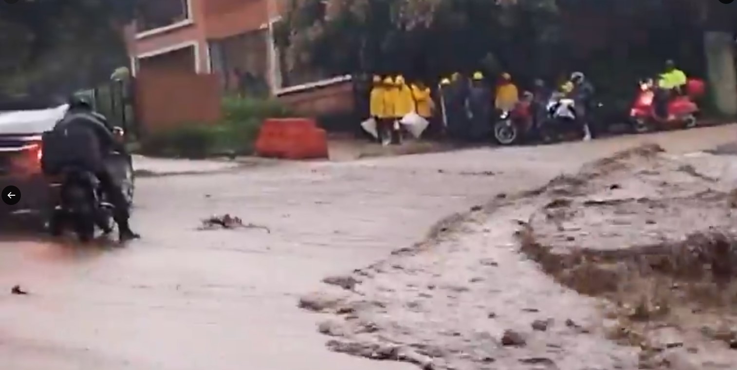 Una fuerte correntada arrastra lodo y piedras sobre la ruta a Muxbal, donde el tránsito permanece bloqueado en ambos sentidos. (Foto Prensa Libre: Captura de Pantalla)