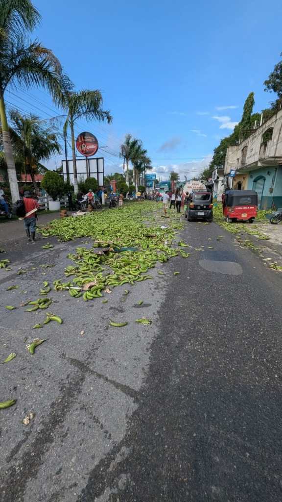 Imagen de la carretera con los bananos esparcidos y el tráiler detenido al fondo.
