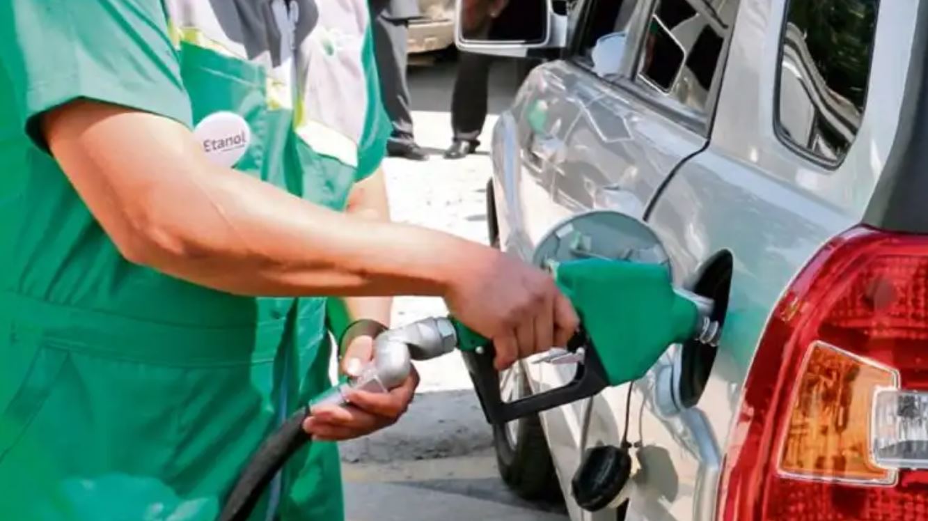Persona llenando el tanque de gasolina mezclada con etanol a un vehículo