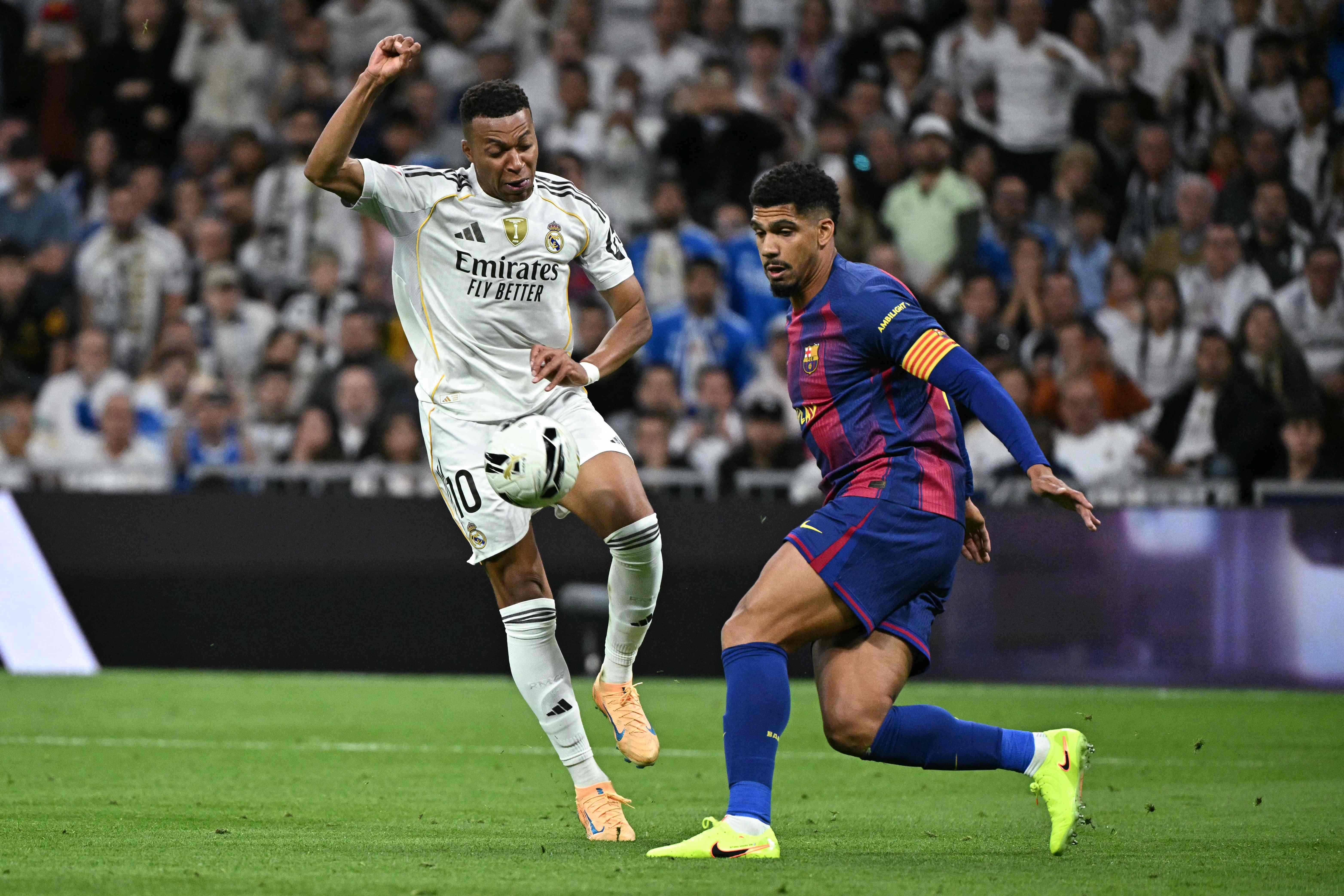 Barcelona's Uruguayan defender #04 Ronald Federico Araujo da Silva (R) vies for the ball with Real Madrid's French forward #10 Kylian Mbappe during the Spanish league football match between Real Madrid CF and FC Barcelona at the Santiago Bernabeu stadium in Madrid on October 26, 2025. (Photo by JAVIER SORIANO / AFP)