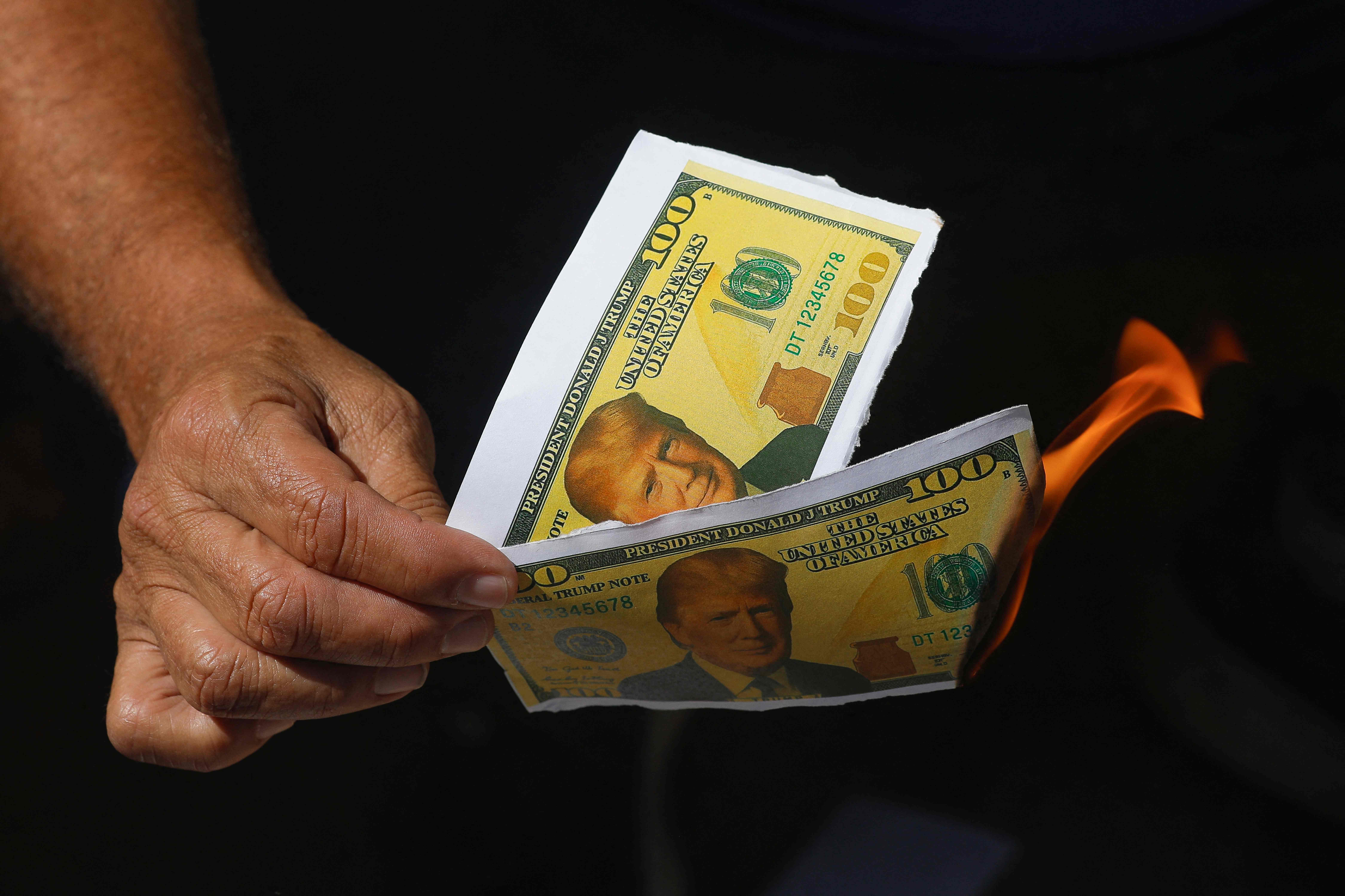 Protesters burn papers imitating US dollar bills during a protest in defense of national sovereignty after trade tariffs and sanctions imposed by the US government on Brazil, near the US embassy in Brasilia, Brazil, on August 1, 2025. Trump's Brazil tariff is among the highest imposed on US trading partners, and unlike with other countries, the measures have been framed in openly political terms, sweeping aside centuries-old trade ties and a surplus that Brasilia put at $284 million last year. (Photo by Sergio Lima / AFP)