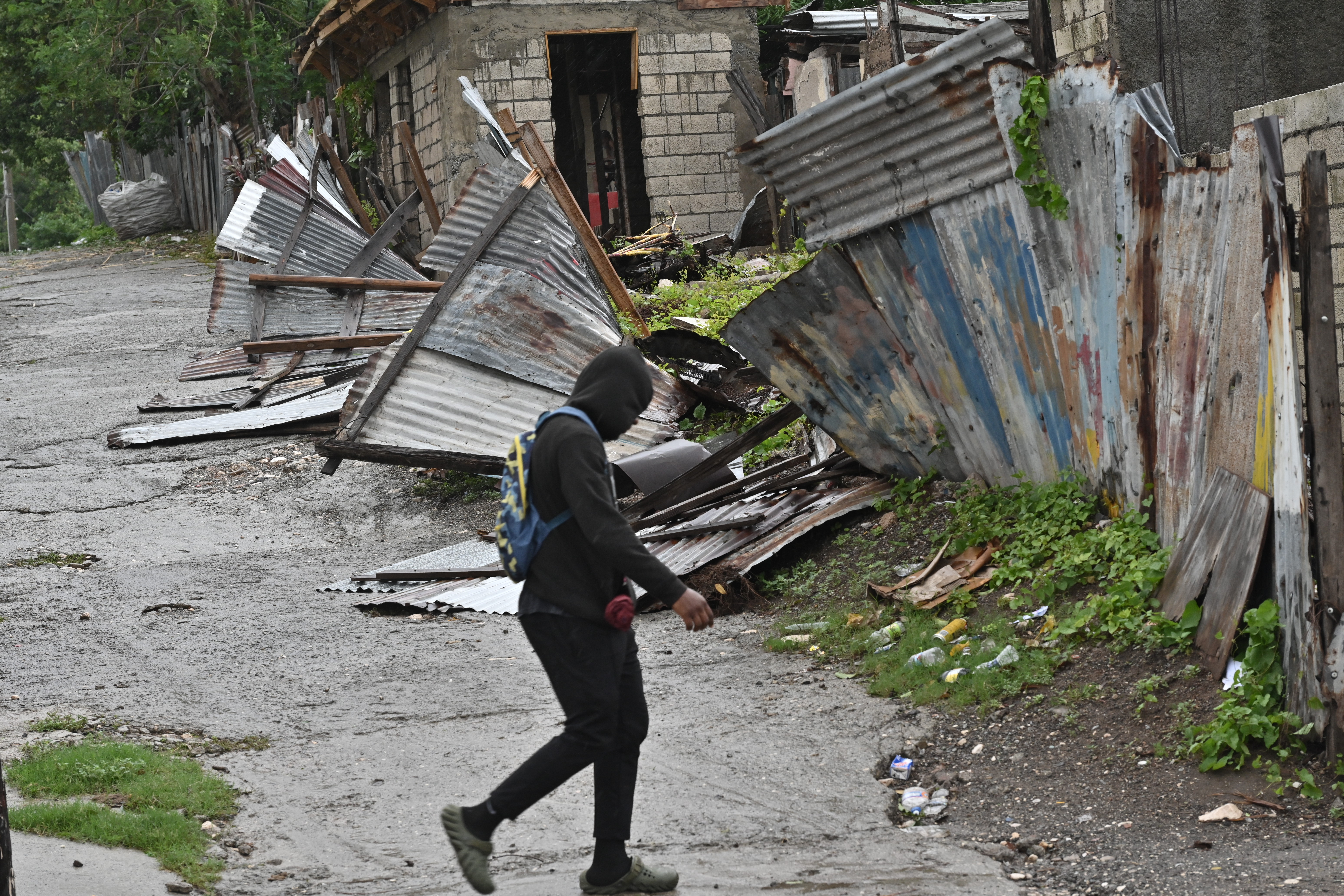 USA5818. KINGSTON (JAMAICA), 28/10/2025.- Una persona camina frente a una casa afectada por el paso del huracán Melissa este martes, en Kingston (Jamaica). El potente huracán Melissa tocó tierra en Jamaica con vientos máximos sostenidos cercanos a los 295 kilómetros por hora (185 millas), lluvias torrenciales y marejadas que amenazan con provocar inundaciones y daños catastróficos. EFE/Rudolph Brown