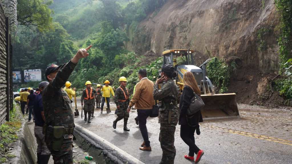 Personas cruzan a pie la zona bloqueada por el derrumbe mientras se desarrollan trabajos.