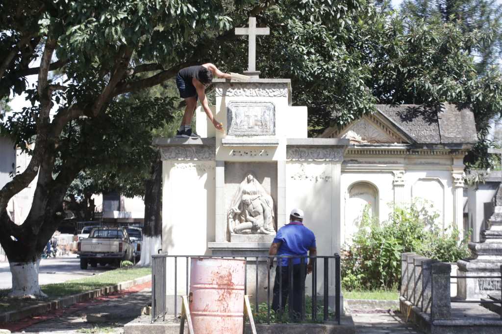 Personas haciendo limpieza y colocando adornos en el Cementerio General.