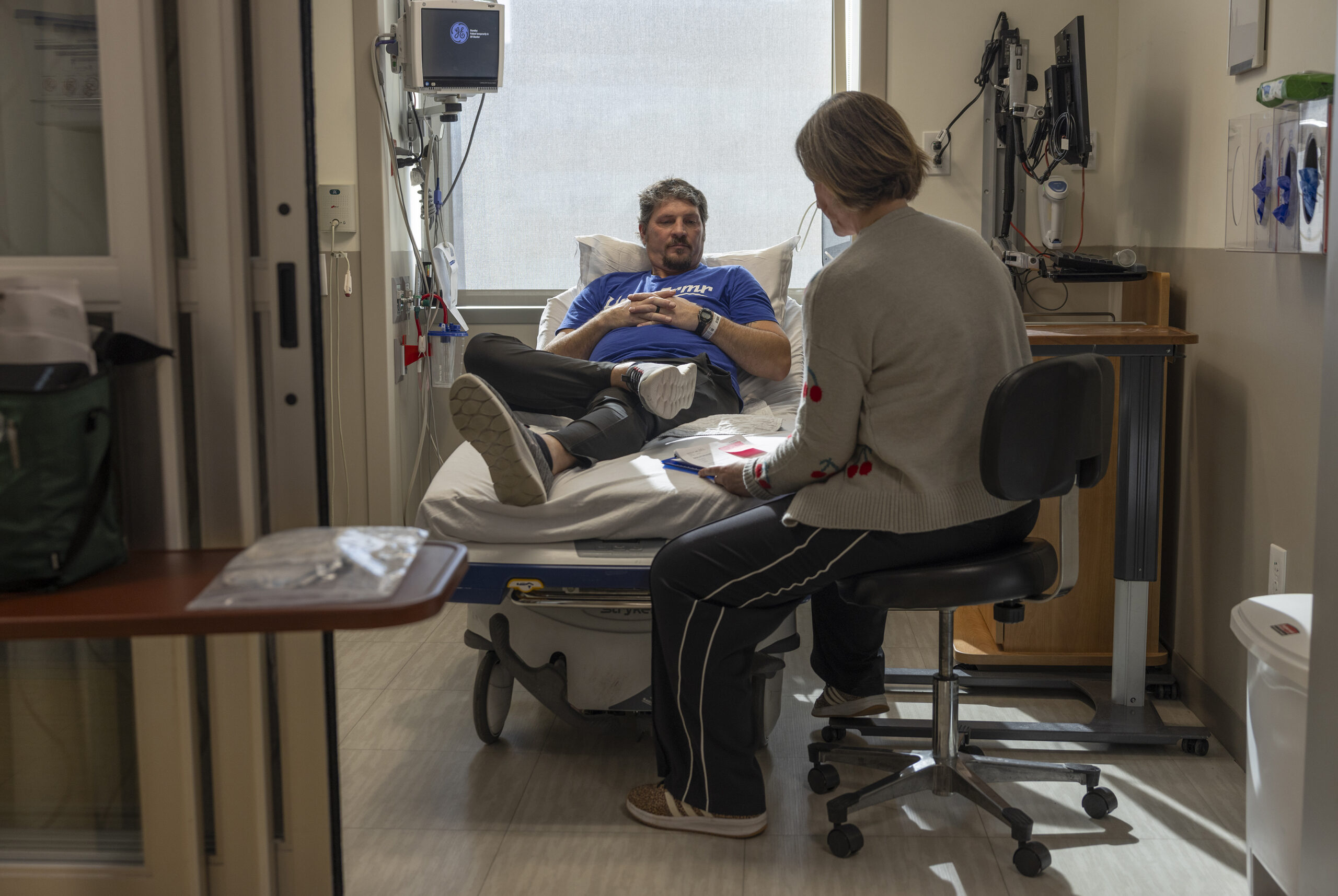 Rickey Malloy, who was diagnosed with ALS in July 2023, with the nurse Kelly McCoy Gross, after receiving an infusion in St. Louis, on Jan. 27, 2026. The drug, tofersen, made by Biogen and marketed as Qalsody, is for a small subset of patients. But evidence that breathing and strength can get better for some of them is remarkable for a paralyzing, usually fatal disease. (Julia Rendleman/The New York Times)